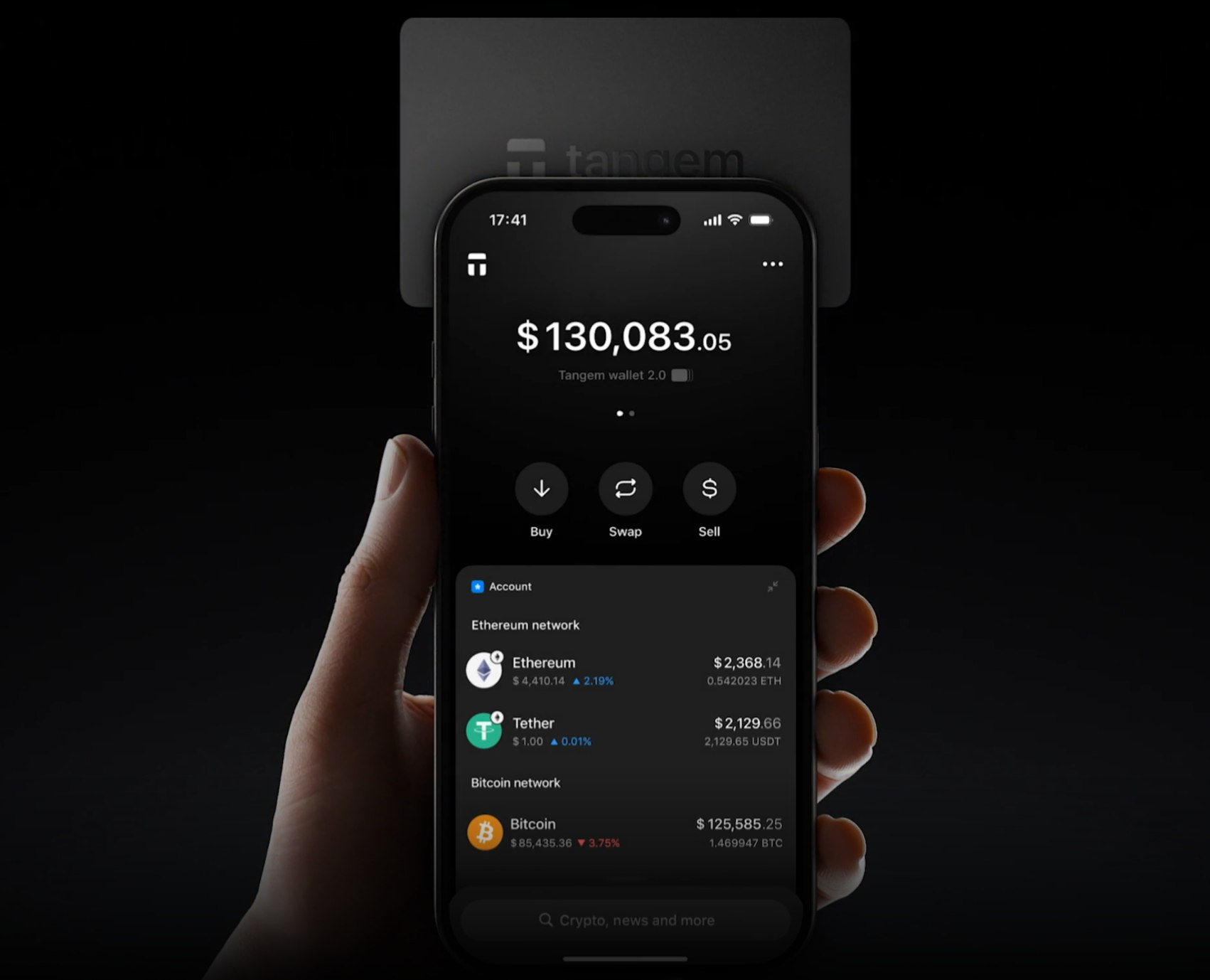 Hand holding iPhone running Tangem Wallet with a Tangem card tapped on top